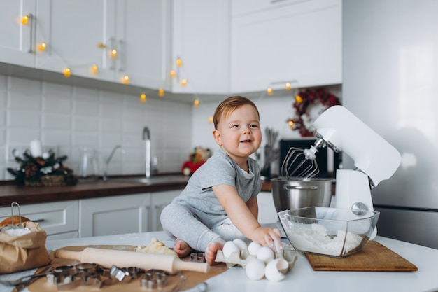 Il ragazzo divertente della famiglia felice che prepara la pasta, cuoce i biscotti nella cucina