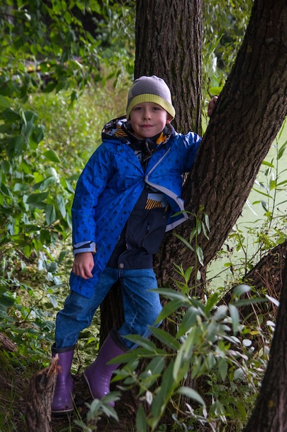 Il ragazzo è appoggiato a un albero. Vicino al salice verde in autunno