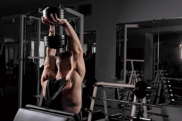 Il ragazzo è impegnato in palestra con i manubri il concetto di vita sportiva