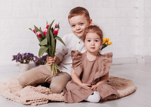 Il ragazzo e la ragazza, il fratello e la sorella si siedono in una stanza bianca con i fiori