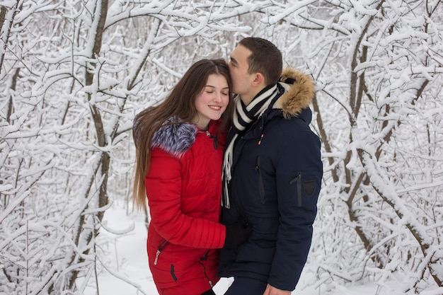 Il ragazzo e la ragazza si riposano nei boschi d'inverno Marito e moglie nella neve Giovane coppia che cammina nel parco invernale