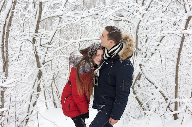 Il ragazzo e la ragazza si riposano nei boschi d'inverno Marito e moglie nella neve Giovane coppia che cammina nel parco invernale