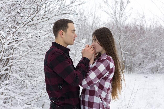 Il ragazzo e la ragazza si riposano nei boschi invernali Marito e moglie nella neve Coppia giovane