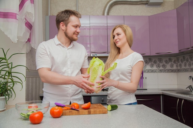 Il ragazzo e la ragazza stanno preparando un'insalata in cucina