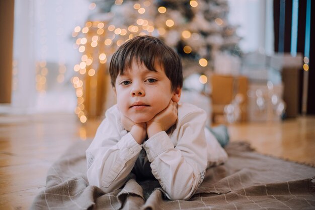 Il ragazzo è sdraiato sotto lo stile di vita dell'albero di Capodanno. Capodanno e Natale.