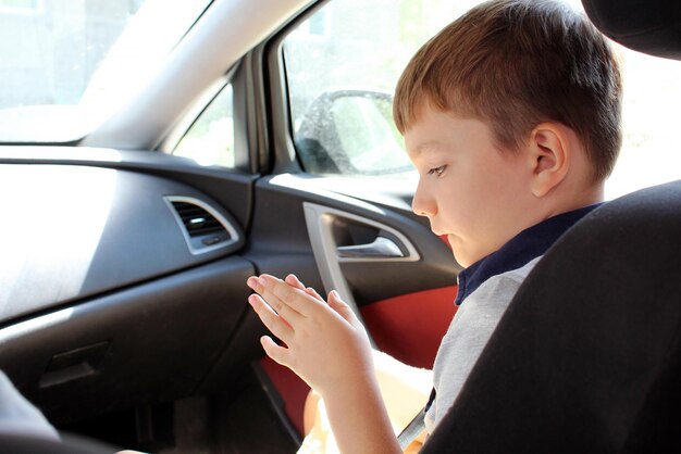 Il ragazzo è seduto sul sedile anteriore dell'auto ritratto in closeup