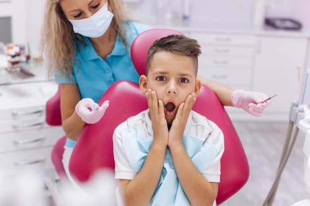 Il ragazzo è spaventato e chiude la bocca con le mani in visita dal dentista presso la clinica odontoiatrica