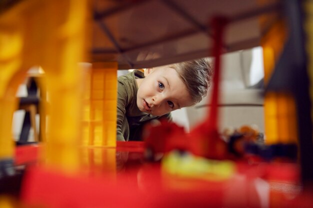 Il ragazzo esplora mentre gioca. Una foto di un bambino che gioca con i giocattoli in casa. Un'infanzia felice all'asilo, lo sviluppo del bambino. Educazione dei bambini all'asilo, giocare e crescere