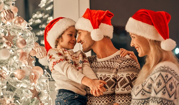 Il ragazzo felice con i genitori sullo sfondo dell'albero di Natale