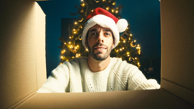 Il ragazzo felice guarda dentro una scatola di Natale