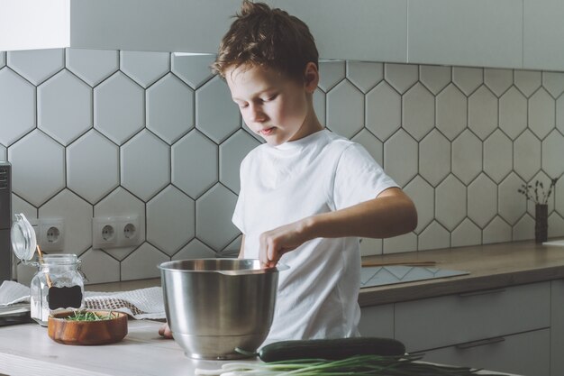 Il ragazzo frusta l'omelette con la frusta