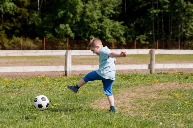 Il ragazzo gioca a calcio in una camicia blu