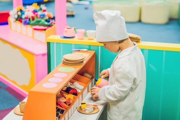 Il ragazzo gioca come se fosse un cuoco o un fornaio in una cucina per bambini