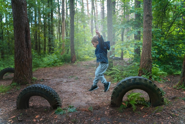 Il ragazzo gioca nel bosco e salta sopra gli ostacoli