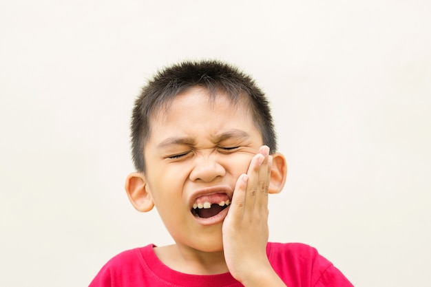 Il ragazzo gli sta tenendo la mano sulla guancia e il viso arrossato dal dolore al mal di denti.