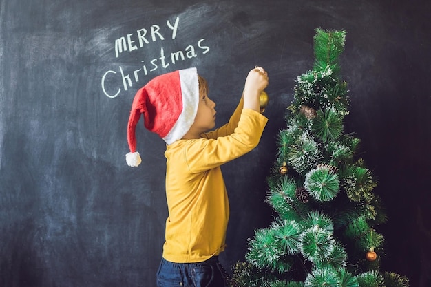 Il ragazzo ha scritto un'iscrizione Merry Cristmas. Albero di Natale. Natale bambino e vacanze di Capodanno