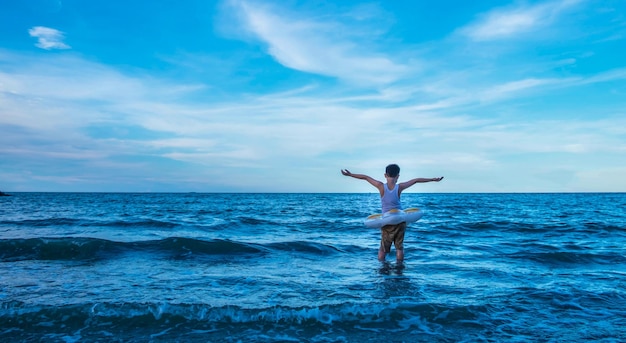 Il ragazzo in piedi in mezzo alle onde dell'oceano Sentendosi coraggioso sfida l'avventura in mare