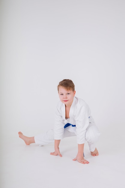 Il ragazzo in un kimono bianco fa un tratto su un muro bianco