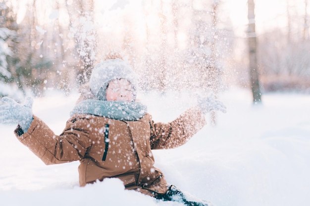 Il ragazzo lancia la neve nello stile di vita invernale Passeggiate invernali Un articolo sul tempo libero invernale dei bambini