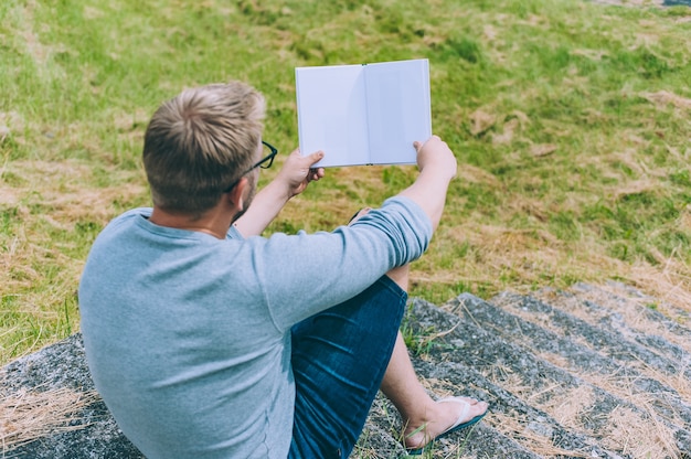 Il ragazzo legge un libro all'aperto sull'erba