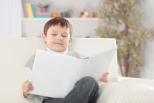 Il ragazzo legge un libro sul divano nella foto del vivaio con lo spazio della copia