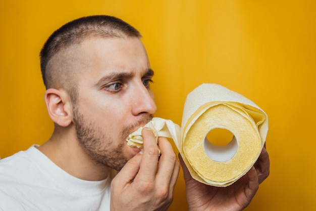 Il ragazzo mangia avidamente carta igienica Il concetto di carta igienica ipercomprata durante il coronavirus Virus pandemico di panico