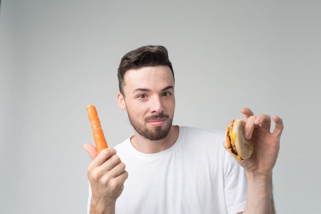 Il ragazzo mangia una carota e un hamburger
