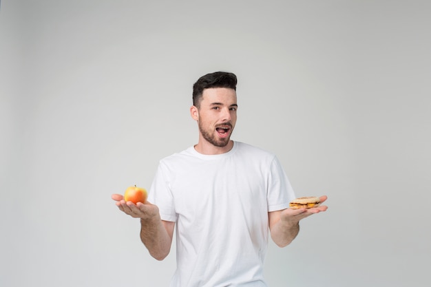 Il ragazzo mangia una mela e un hamburger