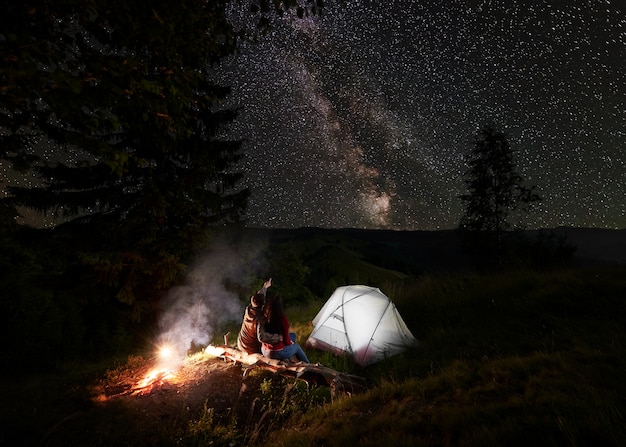 Il ragazzo mostra la ragazza sul cielo stellato di sera