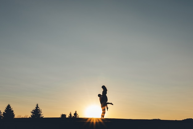 Il ragazzo prese la ragazza tra le braccia al tramonto