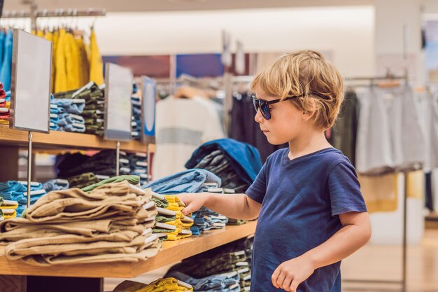 Il ragazzo prova i vestiti nel negozio di abbigliamento per bambini