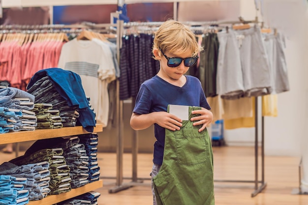 Il ragazzo prova i vestiti nel negozio di abbigliamento per bambini.