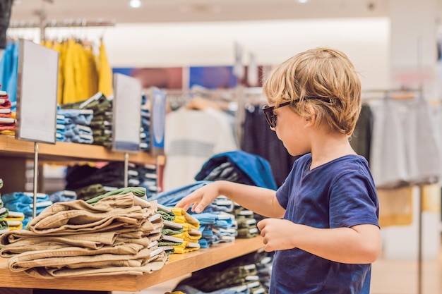 Il ragazzo prova i vestiti nel negozio di abbigliamento per bambini.