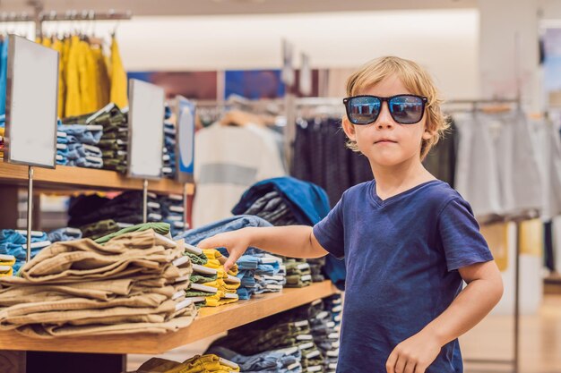 Il ragazzo prova i vestiti nel negozio di abbigliamento per bambini.