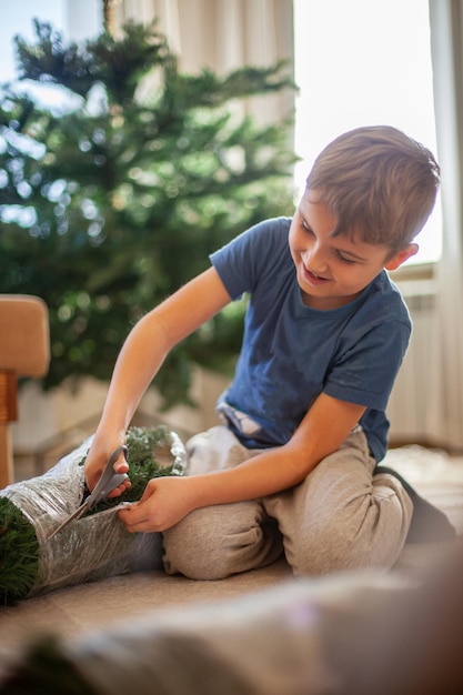 Il ragazzo raccoglie un albero di Natale artificiale a casa in soggiorno