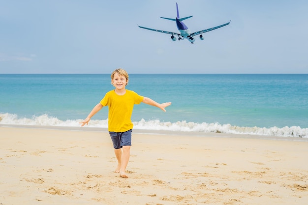 Il ragazzo si diverte sulla spiaggia a guardare gli aerei di atterraggio Viaggiando su un aereo con il concetto di bambini