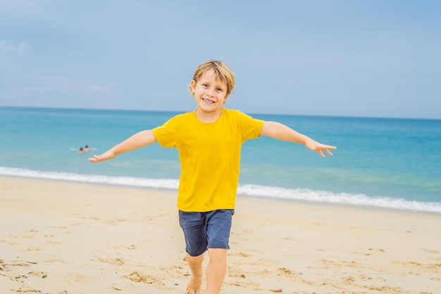 Il ragazzo si diverte sulla spiaggia a guardare gli aerei di atterraggio Viaggiando su un aereo con il concetto di bambini