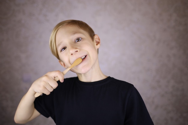 Il ragazzo si lava i denti con un pennello ecologico in materiale naturale