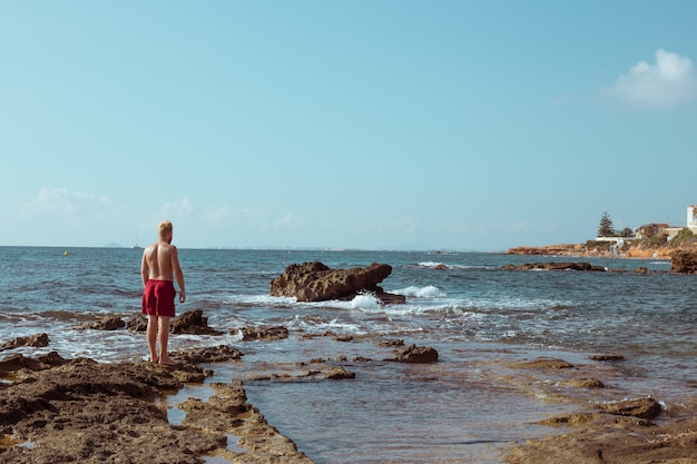 Il ragazzo si trova sugli scogli in riva al mare