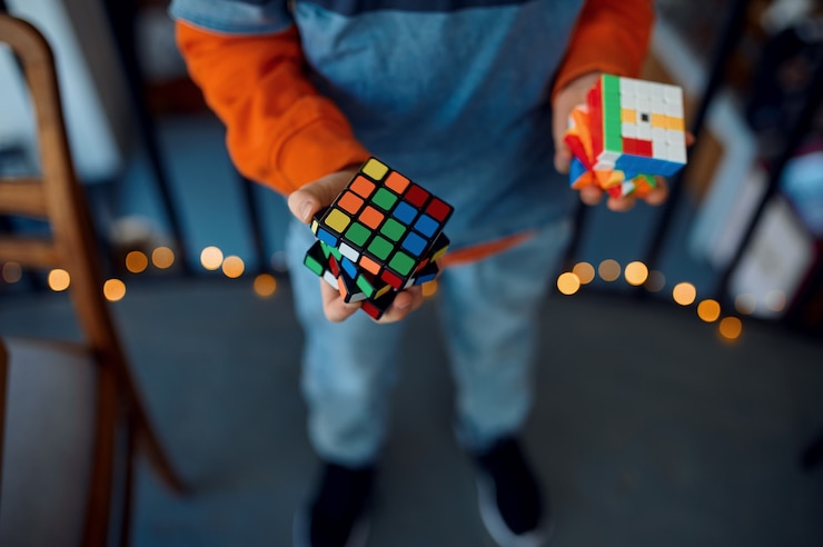 Foto il ragazzo sorridente tiene il cubo di puzzle nelle sue mani. giocattolo per l'allenamento del cervello e della mente logica, gioco creativo, risoluzione di problemi complessi