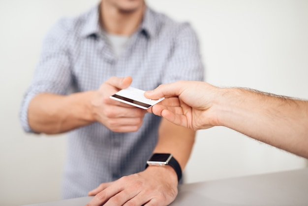 Il ragazzo sta dando la carta di credito al venditore.