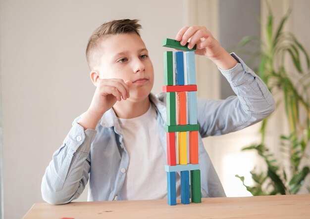 Il ragazzo sta giocando con mattoni di legno colorati costruendo una torre Miglioramento delle capacità motorie Gioca a casa