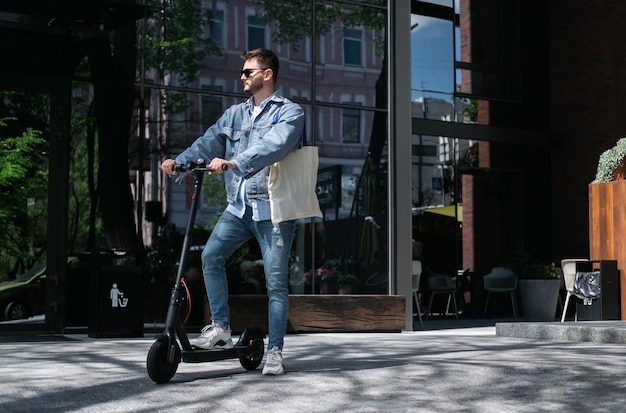 Il ragazzo sta guidando uno scooter elettrico sullo sfondo della città. U cantare il telefono.