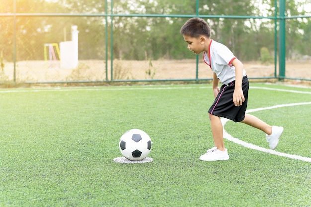 Il ragazzo stava giocando a calcio sul campo di calcio con felicità.