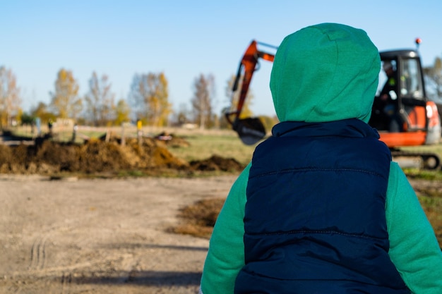 Il ragazzo stava guardando una terna che stava scavando un terreno rurale