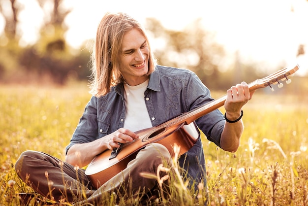 Il ragazzo suona la chitarra in natura