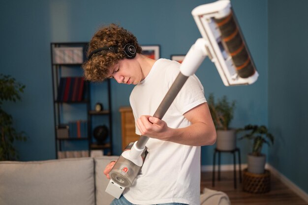 Il ragazzo suona la sera mentre l'adolescente delle pulizie tiene l'aspirapolvere come una chitarra e balla