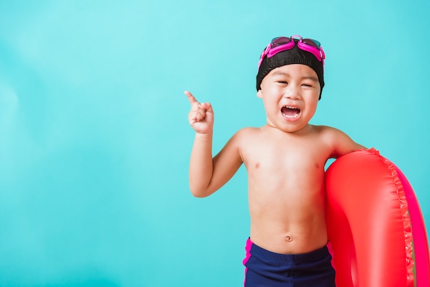 Il ragazzo sveglio del bambino piccolo indossa gli occhiali di protezione e l'anello gonfiabile dell'anguria della tenuta del costume da bagno