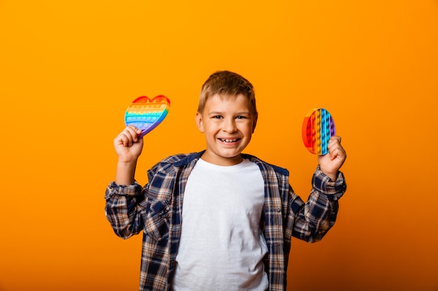 Il ragazzo tiene in mano giocattoli sensoriali che svolazzano. Spingere il gioco pop-it. Ragazzo felice con pop it