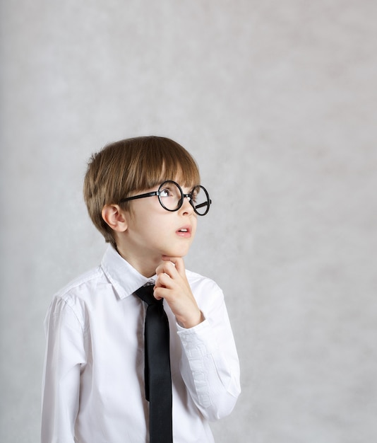 Il ragazzo vestito con una camicia bianca con cravatta nera sta osservando qualcosa